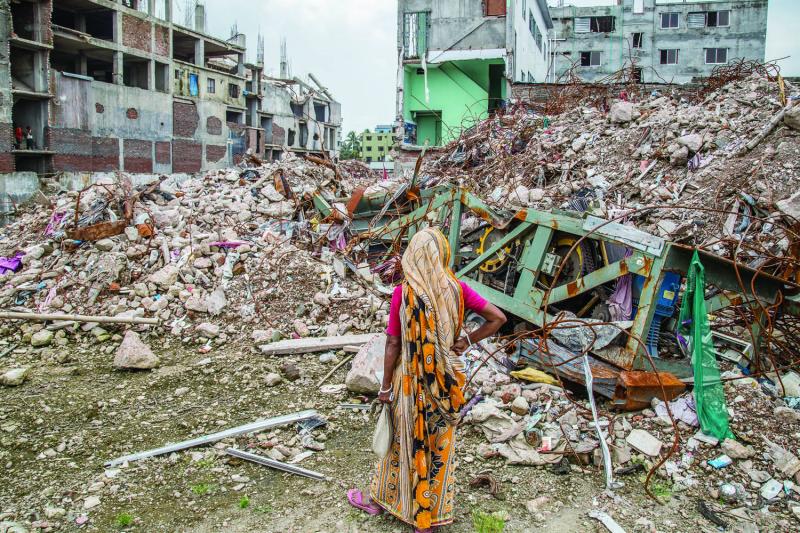 The mother of a missing garment worker stares at the ruins of Rana Plaza in August 2013. Image by Jason Motlagh. Bangladesh, 2013.