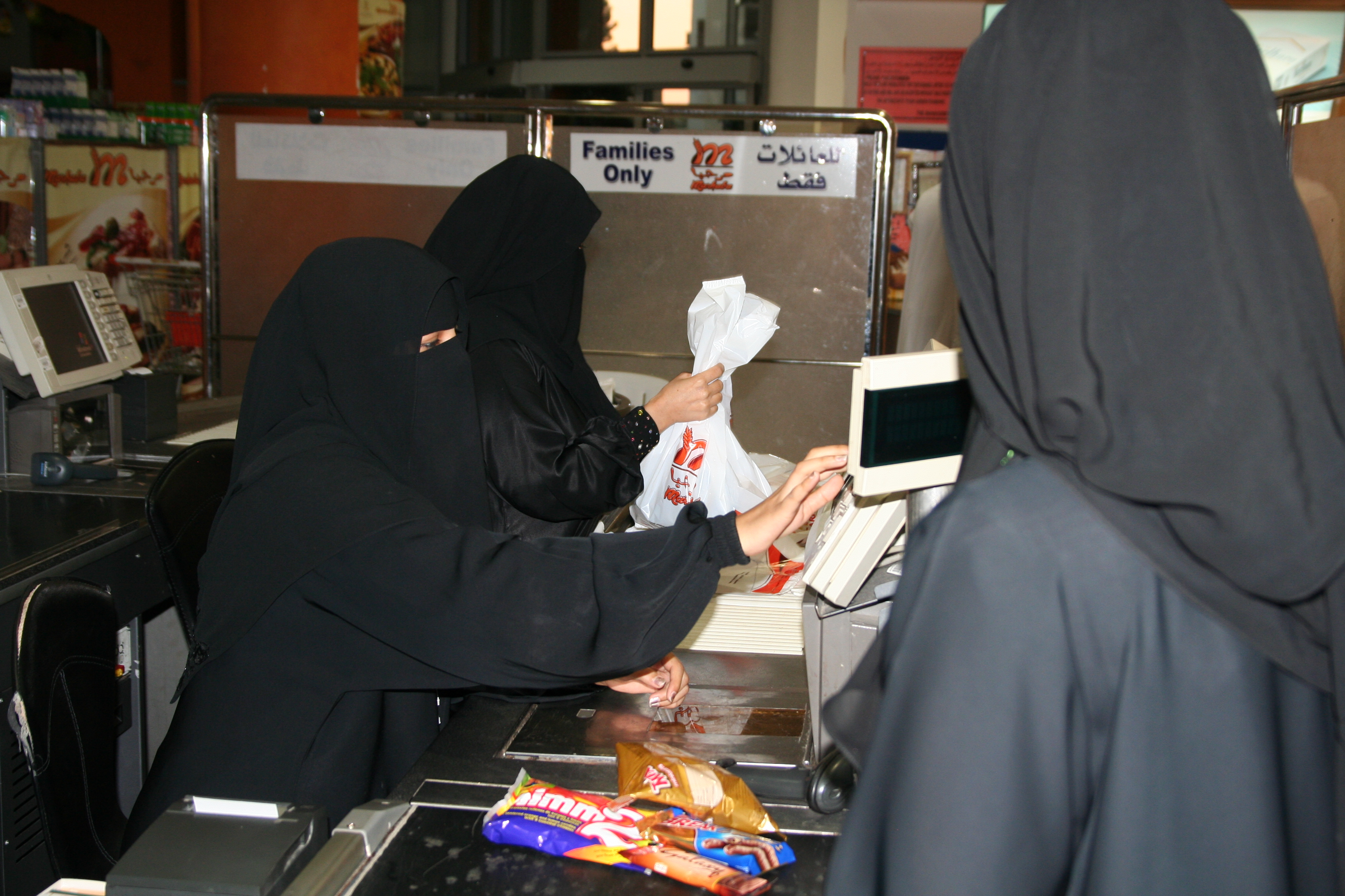 Pioneer female supermarket cashiers. Despite widespread objections from some religious clerics and a significant part of Saudi society, the government is supporting women working. Retail is a big opportunity and it is now common to see women working as store clerks and cashiers. However, only women or men accompanied by a female relative, can use the check-outs staffed by women. Image by Caryle Murphy. Jeddah, 2010. Media file: pioneer_female_cashiers._image_by_caryle_murphy_jeddah_2010jpg.jpg