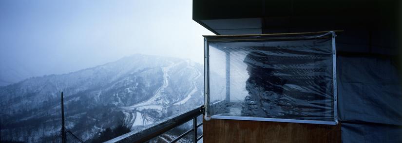 A South Korean soldier looks out from observation post No. 717, the easternmost outpost in South Korea. The two fences on the hillside in the background mark out the mine-filled strip of land at the center of the DMZ. Image © Tomas van Houtryve/VII. South Korea, 2013. Media file: 008_web_edit_BorderlineNK.jpg