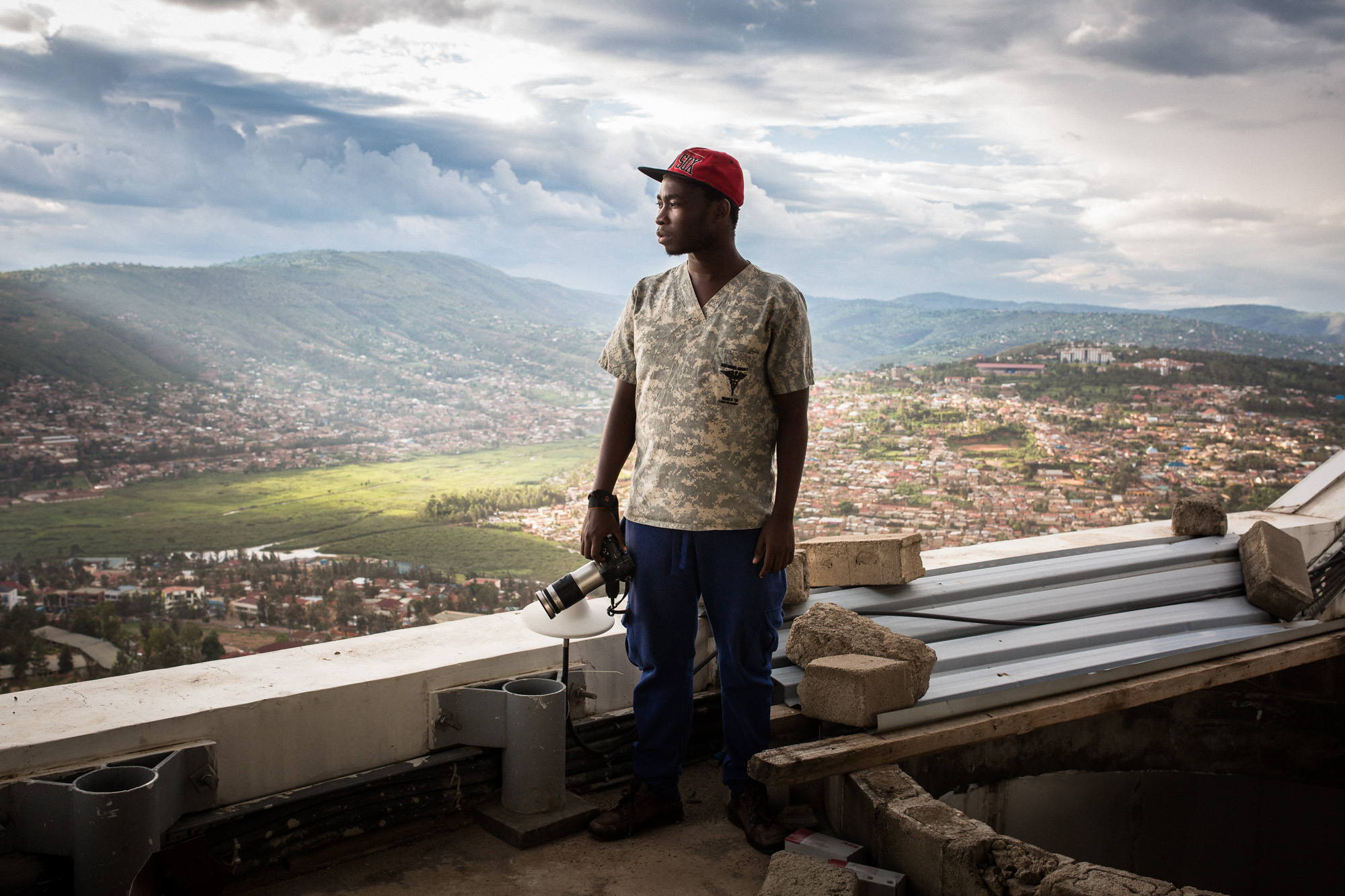 Jack Yakubu Nkinzingabo, a young Rwandan photographer, stands on Kigali City Tower, the highest roof in Rwanda's capital city. Image by Juan Herrero. Rwanda, 2015. Rwanda's young generation. Pportrait of photographer Yakubu.
