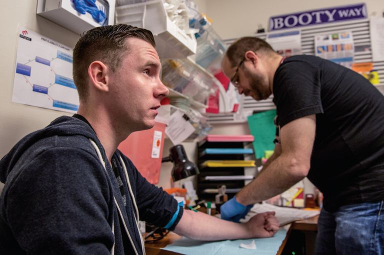 Shane Ryan After this test showed Shane Ryan's blood was negative for the AIDS virus, Magnet's nurse practitioner Pierre-Cédric Crouch (background) offered him anti-HIV drugs to prevent infection. Image by Drew Bird for Jon Cohen's "End of AIDS" project. United States, 2015.