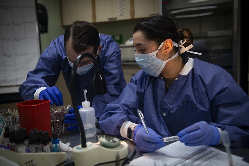 U.S. Navy Hospital Corpsman 3rd Class Janet Rosas (right,) and Hospital Corpsman 2nd Class Cecil Dorse test blood samples aboard the Military Sealift Command hospital ship USNS Comfort in New York City. Image courtesy of U.S. Navy Mass Communication Specialist 2nd Class Sara Eshleman. United States, 2020. U.S. Navy Hospital Corpsman 3rd Class Janet Rosas (right,) and Hospital Corpsman 2nd Class Cecil Dorse test blood samples aboard the Military Sealift Command hospital ship USNS Comfort in New York City. Image courtesy of U.S. Navy Mass Communication Specialist 2nd Class Sara Eshleman. United States, 2020.