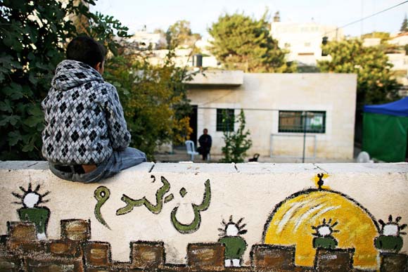 A Palestinian child sitting on a fence in the neighborhood of Sheikh Jarrah. Image by Daniel Bar-On/Redux. Jerusalem, 2013.