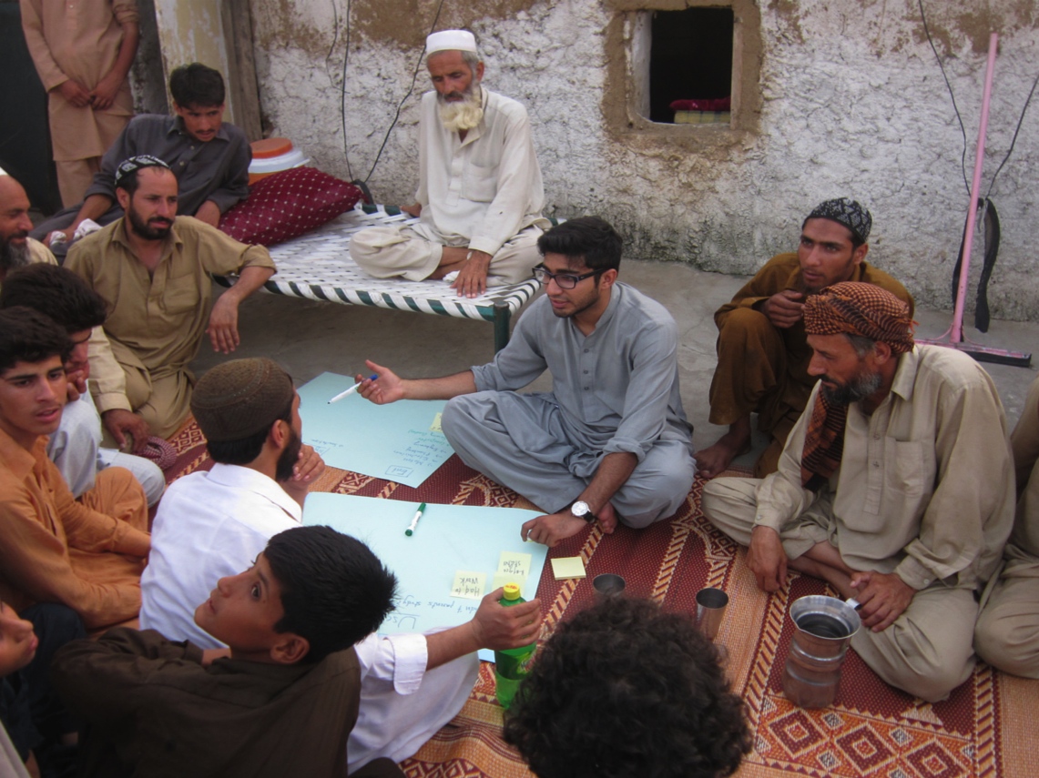Haroon Yasin, co-founder of the Orenda Project, speaks with the tribal council in Afghan Basti. Image from The Orenda Project's website https://www.indiegogo.com/projects/co-creation-education-integration. Pakistan, 2014. Media file: 20141221062321-cocreation.jpg