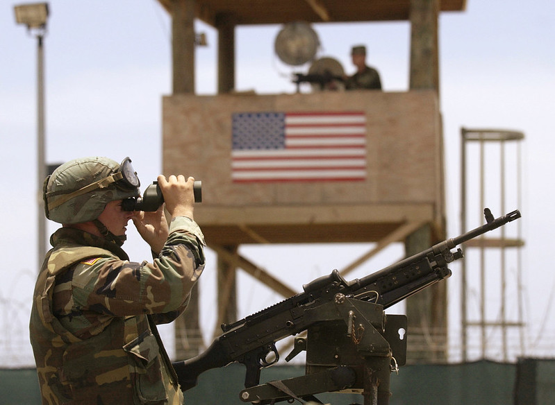A soldier atop a High Mobility Multipurpose Wheeled Vehicle (HMMWV) surveys the area just outside Camp Delta during a detainee escape exercise in Guantanamo Bay, Cuba. Image by U.S. Navy photo by Journalist Chief (SS) John F. Williams. Cuba, 2003. A soldier atop a High Mobility Multipurpose Wheeled Vehicle (HMMWV) surveys the area just outside Camp Delta during a detainee escape exercise in Guantanamo Bay, Cuba. Image by U.S. Navy photo by Journalist Chief (SS) John F. Williams. Cuba, 2003.