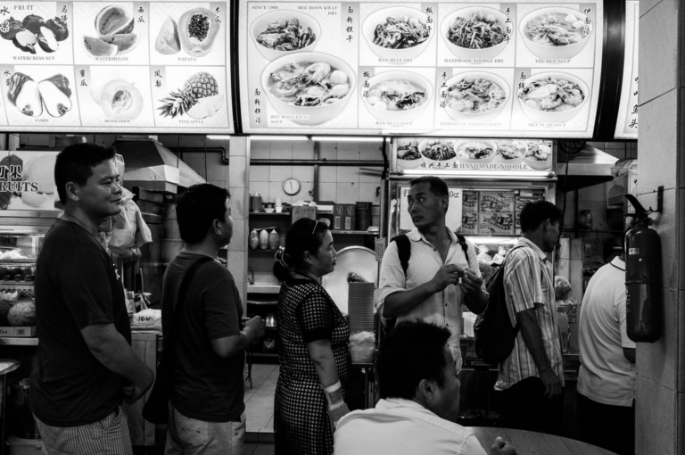 Xi Feng Xi Feng stands in the line with other Chinese migrant workers to get free meal. Image by Xyza Bacani. Singapore, 2017.