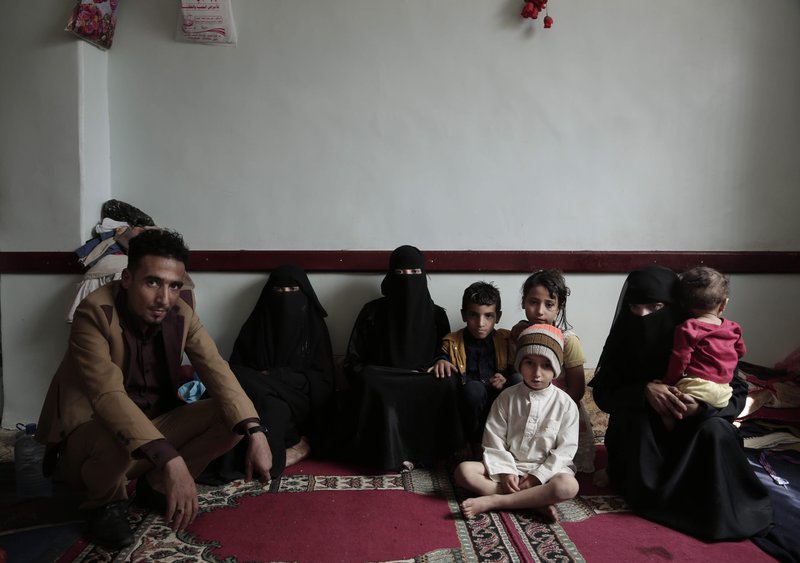 A family poses for a photograph in their room at a shelter for displaced persons in Ibb. Image by Nariman El-Mofty/AP Photo. Yemen, 2018. A family poses for a photograph in their room at a shelter for displaced persons in Ibb. Image by Nariman El-Mofty/AP Photo. Yemen, 2018.