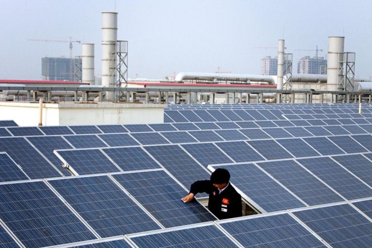 A worker cleans a solar panel on top of a factory building in Baoding City. China is installing a soccer field's worth of solar panels every hour. Image by Sean Gallagher. China, 2017. A worker cleans a solar panel on top of a factory building in Baoding City. China is installing a soccer field's worth of solar panels every hour. Image by Sean Gallagher. China, 2017.