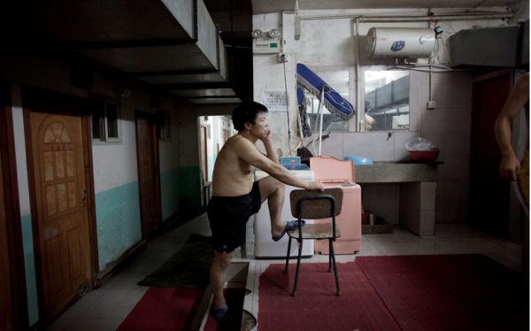 A resident waits to use the communal bathroom and washing area of a basement hostel on the western outskirts of Beijing. Image by Sim Chi Yin. China, August 20, 2011. Media file: chiyin.png
