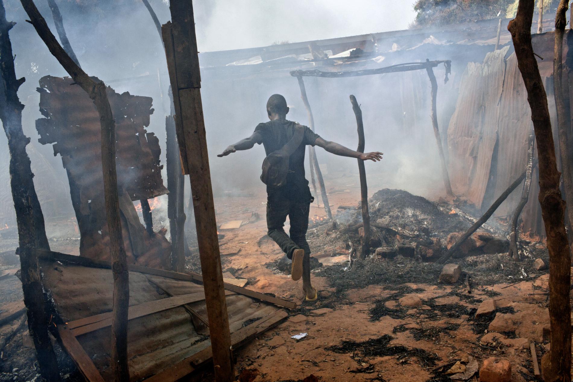 Capital A neighborhood in the capital, Bangui, smolders in 2014 after Christian-led militias attacked predominantly Muslim rebels who had ousted the government. The faiths once coexisted in relative peace, but chaos has reigned in much of the nation for the past four years. Image by Marcus Bleasdale. Central African Republic.