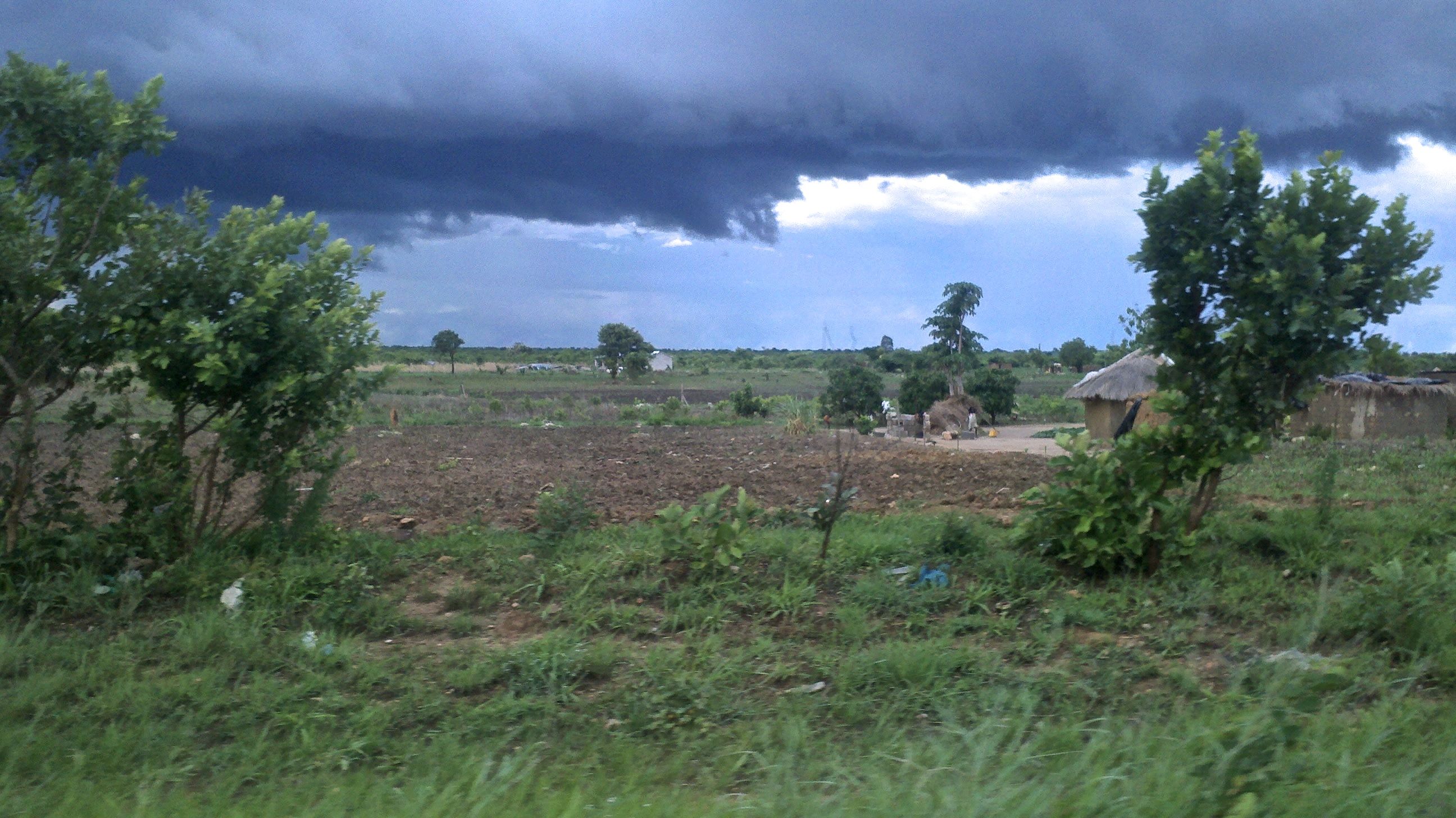 Rain rolls in near the airport outside of Lusaka, Zambia. Leave the city, and it's easy to find signs of rural poverty. Image and caption by Jina Moore. Zambia, 2014. Media file: rain_rolls_in_over_a_hut_near_lusaka_airport.jpg