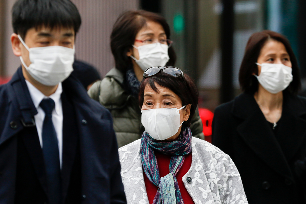 Pedestrians wearing surgical masks to prevent infectious diseases walk along the luxury area of Ginza. Japan has confirmed coronavirus infections cases in the country. Image by Shutterstock. Japan, 2020. Pedestrians wearing surgical masks to prevent infectious diseases walk along the luxury area of Ginza. Japan has confirmed coronavirus infections cases in the country. Image by Shutterstock. Japan, 2020.