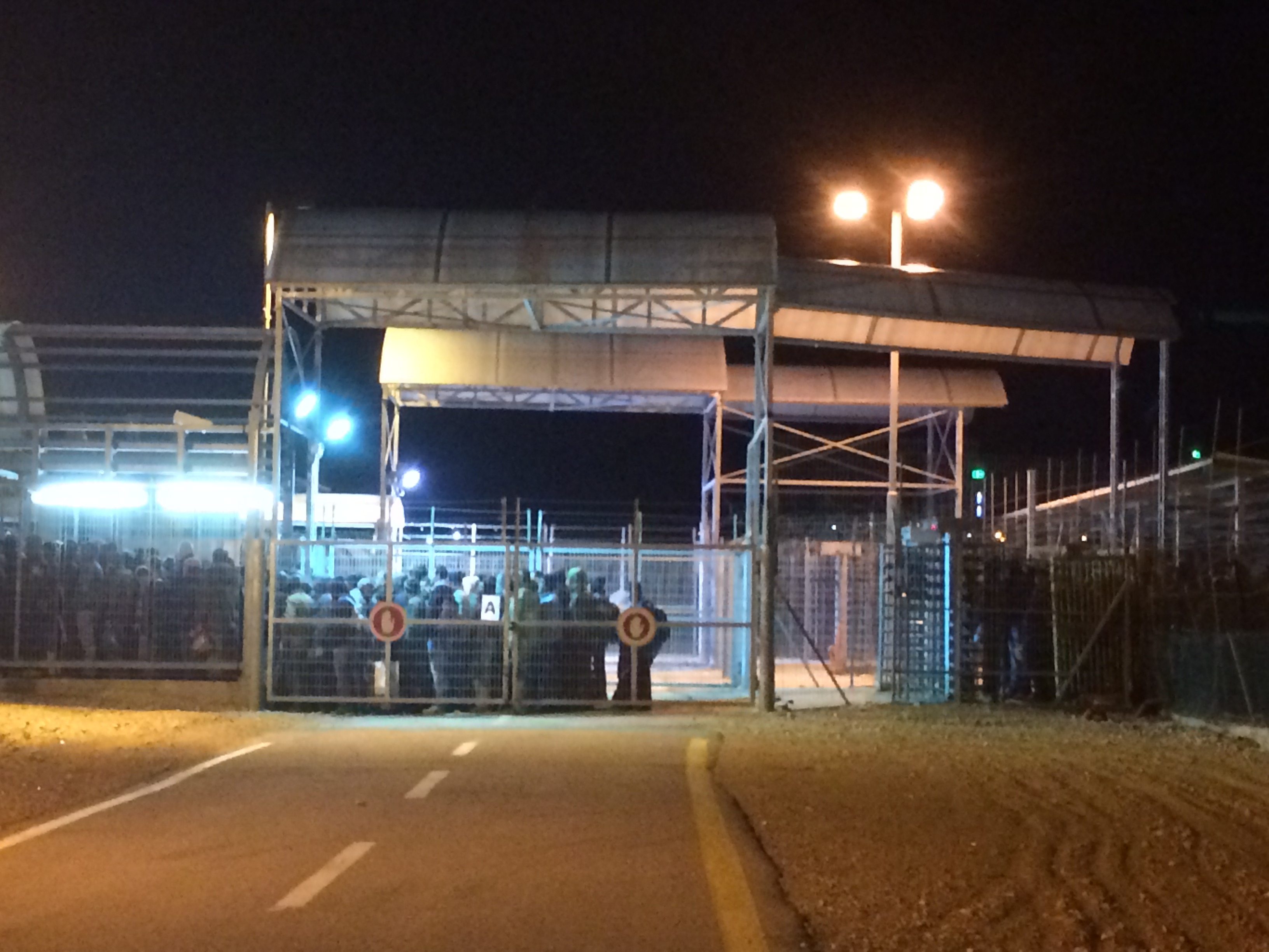 Palestinian men who labor in Israel wait to cross from the Palestinian to the Israeli side of the Eyal checkpoint before sunrise in February. Image by Miriam Berger. Israel, 2017. Palestinian men who labor in Israel wait to cross from the Palestinian to the Israeli side of the Eyal checkpoint before sunrise in February. Image by Miriam Berger. Israel, 2017.