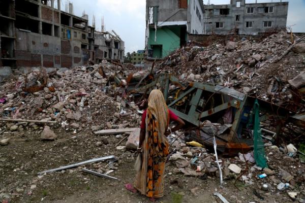 The mother of a missing garment worker stares at the ruins of Rana Plaza in August 2013. Image by Jason Motlagh. Bangladesh, 2013.