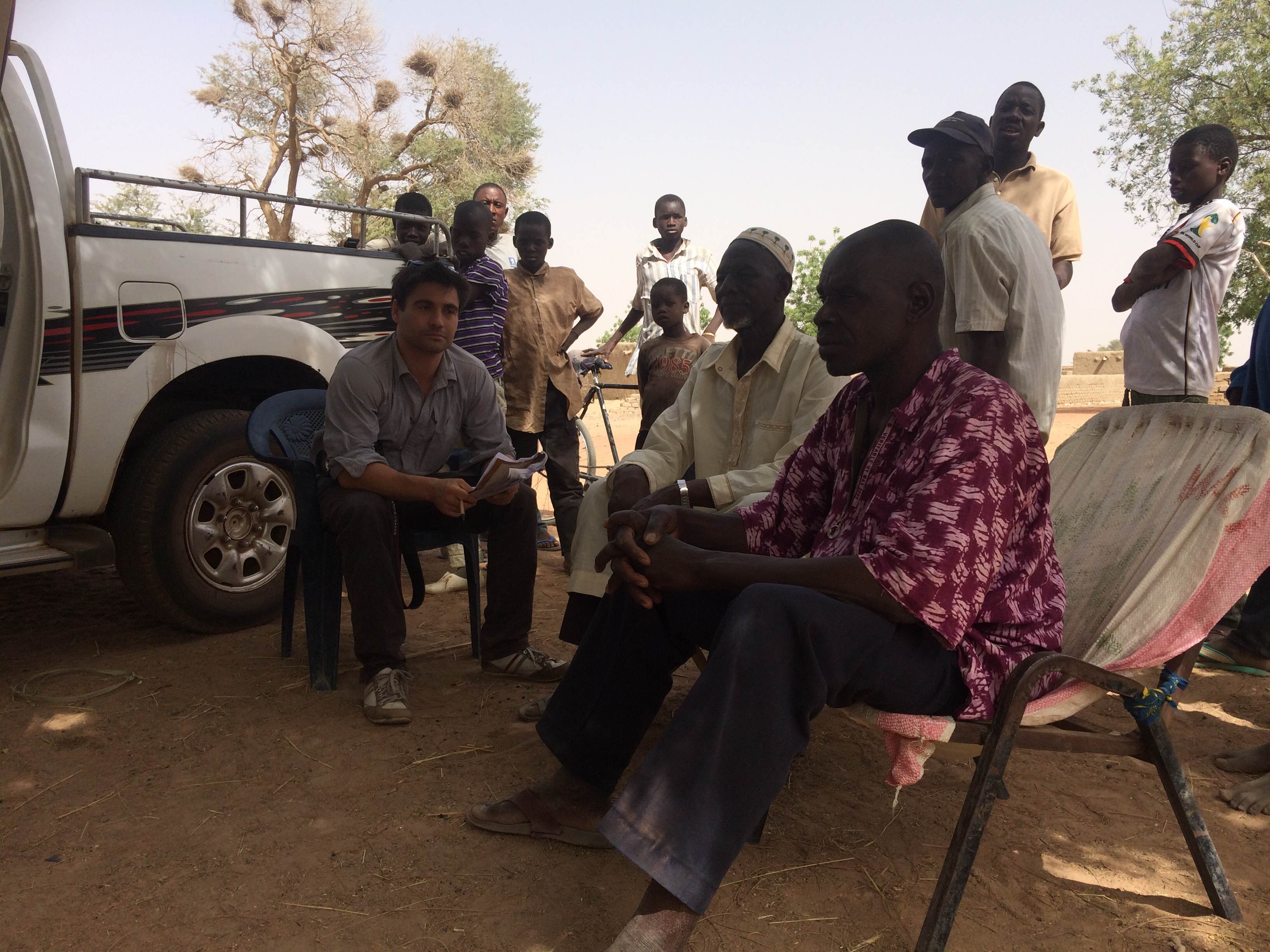 Journalist Chris Arsenault talks with residents of a village inside the Malibya concession. Many worried they could be displaced if the project starts again. Image by Chris Arsenault. Mali, 2015.