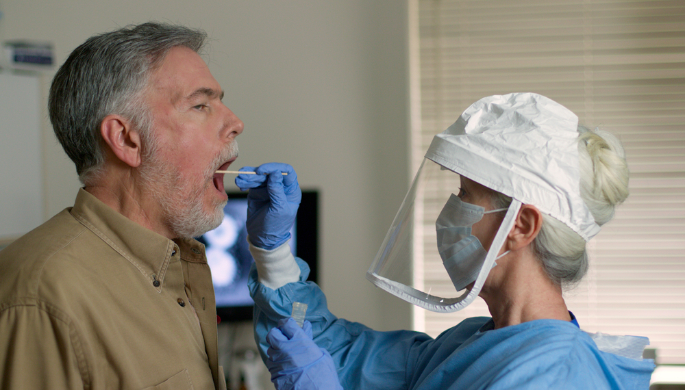 A man being swabbed by a healthcare worker in protective garb to determine if he has contracted the coronavirus. Image by JHDT Productions / Shutterstock. United States, 2020. A man being swabbed by a healthcare worker in protective garb to determine if he has contracted the coronavirus. Image by JHDT Productions / Shutterstock. United States, 2020.