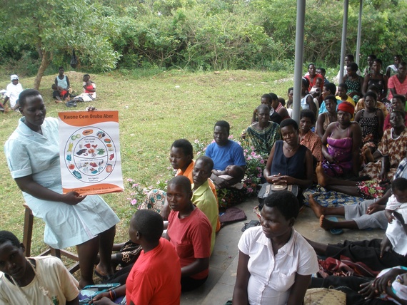 Midwife Susan Ejang explains the importance of good nutrition to a group of pregnant women and new moms gathered on the veranda of a health clinic in northern Uganda. Image by Roger Thurow. Uganda, 2014. Media file: lead.jpg