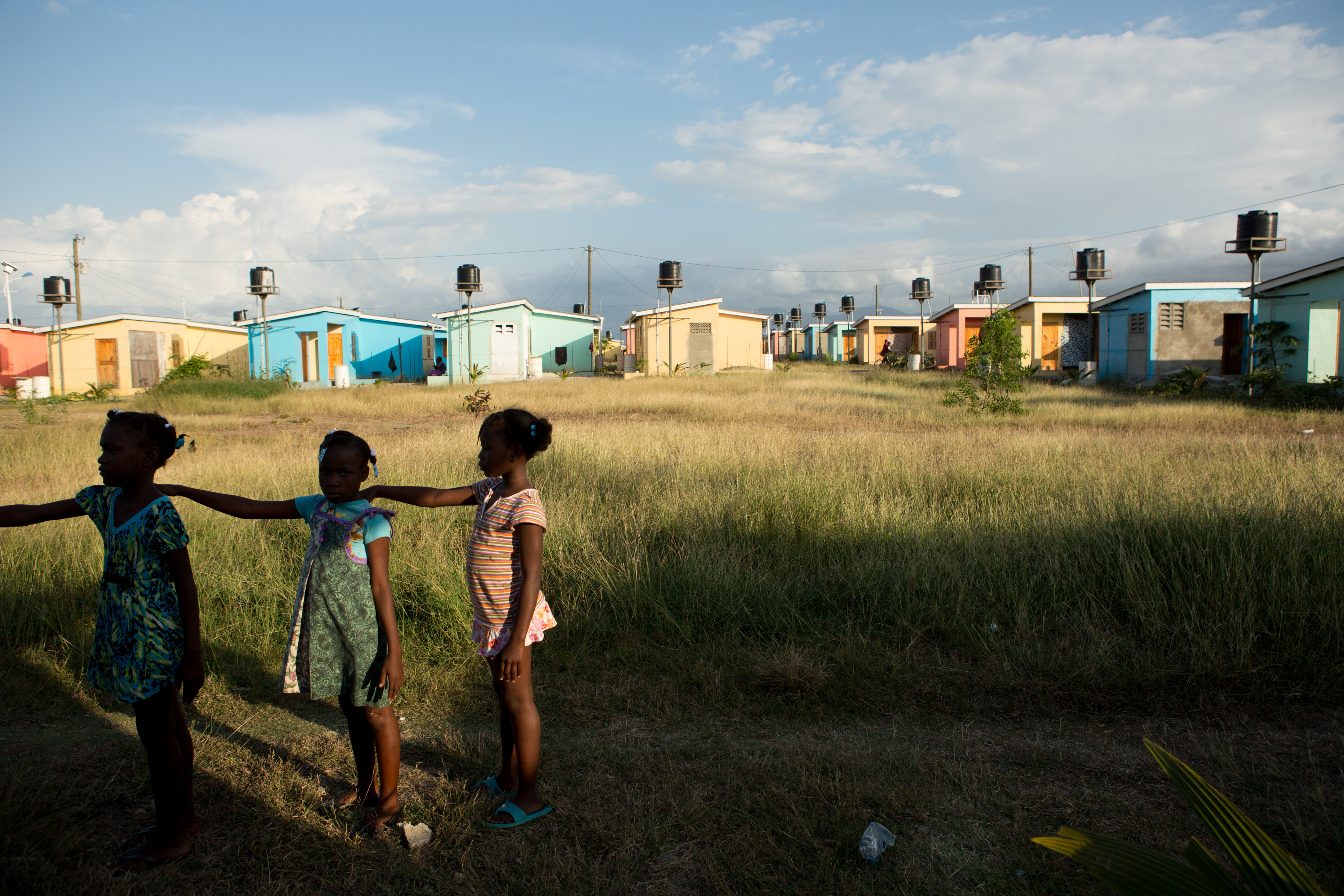Third graders practice a marching drill after school with the help of their teacher Diendonne Daniel in preparation for a Flag Day ceremony to be held on May 18 in the village of La Difference in the north of Haiti, April 15, 2015. The USAID-funded housing project stands alone in the middle of grazing land near the Caracol Industrial Park. The project was initially projected to have 15,000 homes but so far consists of 900 one-bedroom lodgings of such poor quality that USAID has suspended contractors who built them. (photo by Allison Shelley) Media file: clintons_haiti_028.jpg