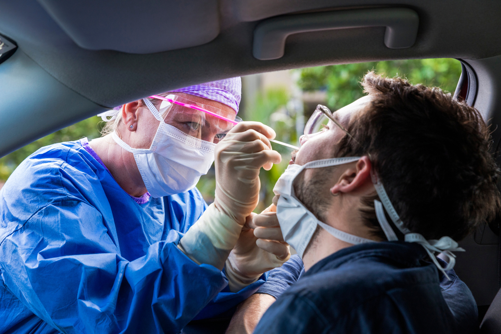 A doctor in a protective suit taking a nasal swab from a person to test for possible coronavirus infection. Image by zstock / Shutterstock. United States, 2020. A doctor in a protective suit taking a nasal swab from a person to test for possible coronavirus infection. Image by zstock / Shutterstock. United States, 2020.