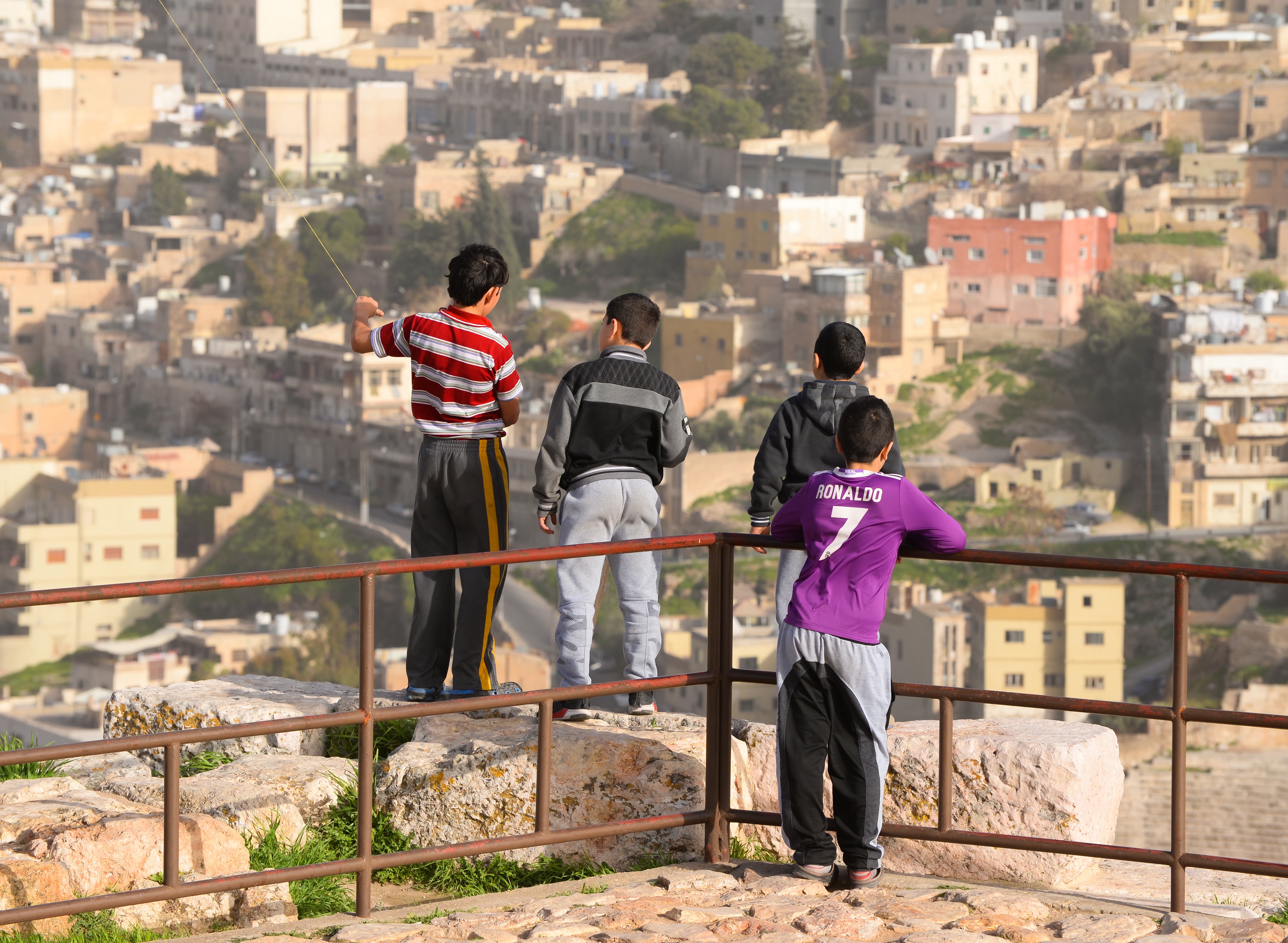 Group of local Jordanian children and city skyline out of focus from the Citadel Hill, Jabal. Image by Thiago B Trevisan / Shutterstock.com. Jordan, 2018. Group of local Jordanian children and city skyline out of focus from the Citadel Hill, Jabal. Image by Thiago B Trevisan / Shutterstock.com. Jordan, 2018.