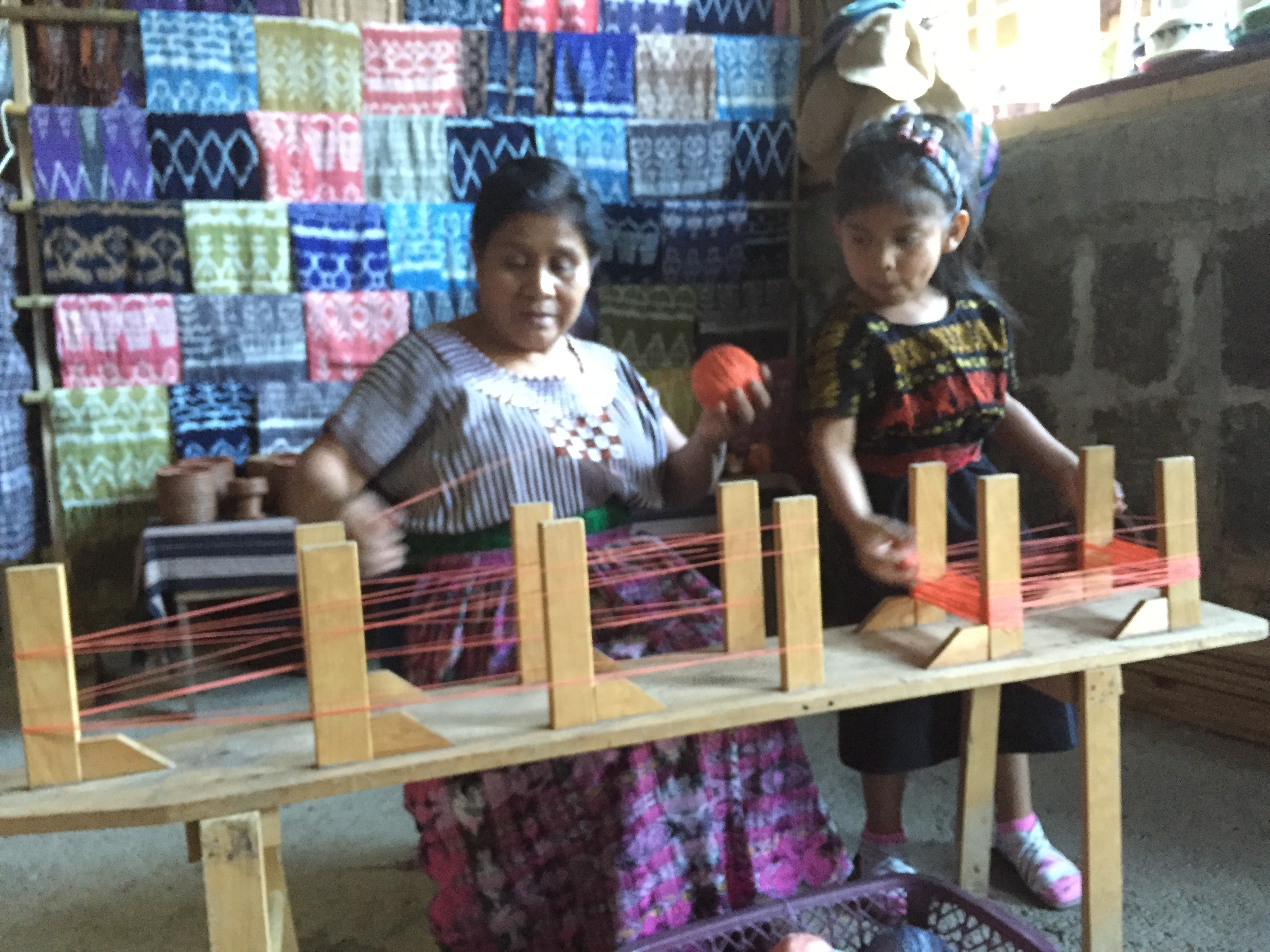Elena Yojcom and her granddaughter weave in front of their shop in San Juan la Laguna. Image by Eric Halperin. Guatemala, 2015. Media file: img_1161.jpg