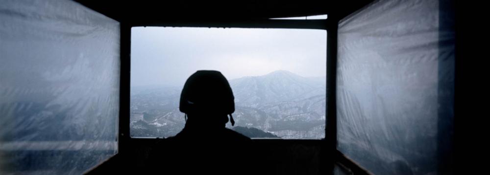 A South Korean soldier looks out over the Demilitarized Zone (DMZ) that separates North and South Korea from a guard position near Goseong. As many as 120,000 North Koreans are thought to be imprisoned across that country, according to a United Nations report that compares conditions in the DMZ to camps run by the Nazis during World War II and gulags set up in Soviet Russia. Image by Tomas van Houtryve. DMZ, 2013.