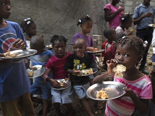 Children at an orphanage in Gressier, Haiti, eat chicken raised by KORE Foundation farmers. The chicken serves as a source of protein to combat malnutrition. Image by Larry McCormack. Haiti, 2016. Media file: 39.jpg