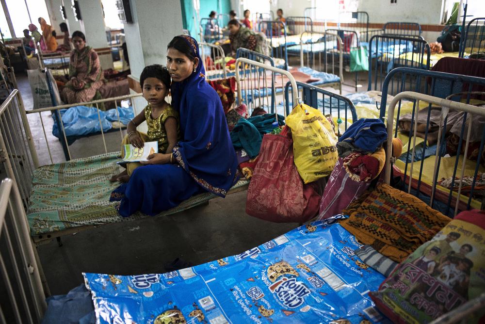 Families use package materials for Western food products, purchased from the small shops outside of the hospital, to cover the poorly maintained hospital beds at the Burdwan medical college hospital. Image by Sami Siva. India, 2014. Media file: hospitalcrisis-india-pulitzer-samisiva-09.jpg