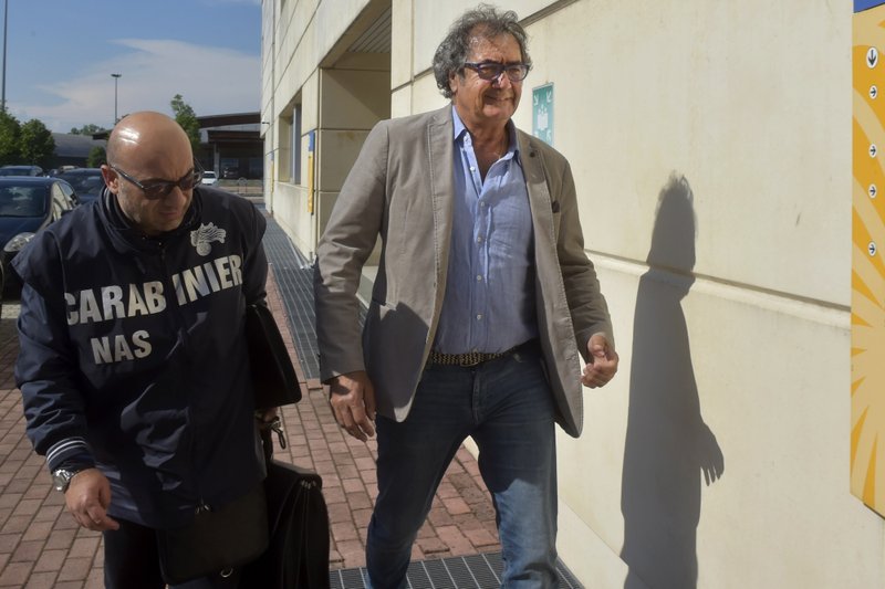 Dr. Guido Fanelli, right, is taken to the Carabinieri headquarters in Parma, Italy, for questioning in an alleged pharmaceutical kickback scheme on Monday, May 8, 2017. That morning, police jolted Fanelli out of bed. It was a spectacular fall from grace for a man who appeared days before on a popular television show to promote painkillers. Image by AP Photo/Marco Vasini. Italy, 2017. Dr. Guido Fanelli, right, is taken to the Carabinieri headquarters in Parma, Italy, for questioning in an alleged pharmaceutical kickback scheme on Monday, May 8, 2017. That morning, police jolted Fanelli out of bed. It was a spectacular fall from grace for a man who appeared days before on a popular television show to promote painkillers. Image by AP Photo/Marco Vasini. Italy, 2017.