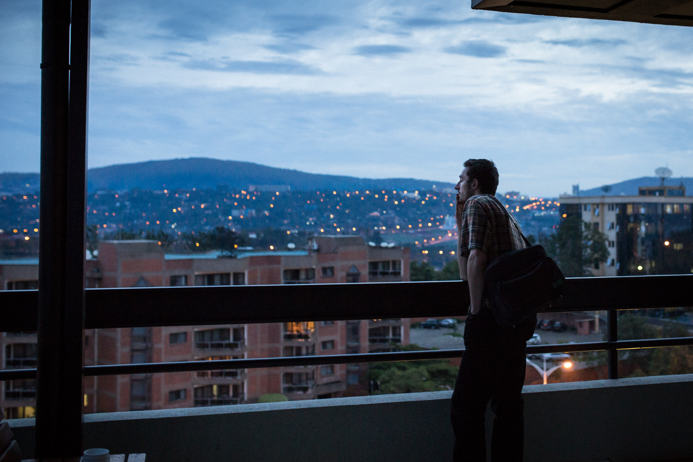 Journalist Wyatt Orme contemplates during dusk overlooking Kigali. Image by Juan Herrero. Rwanda, 2015.
