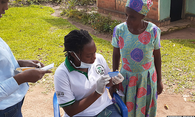 Officials from EPHWOR give out birth control pills to a woman in Buhweju district. Image by Fredrick Mugira. Uganda, undated. Officials from EPHWOR give out birth control pills to a woman in Buhweju district. Image by Fredrick Mugira. Uganda, undated.