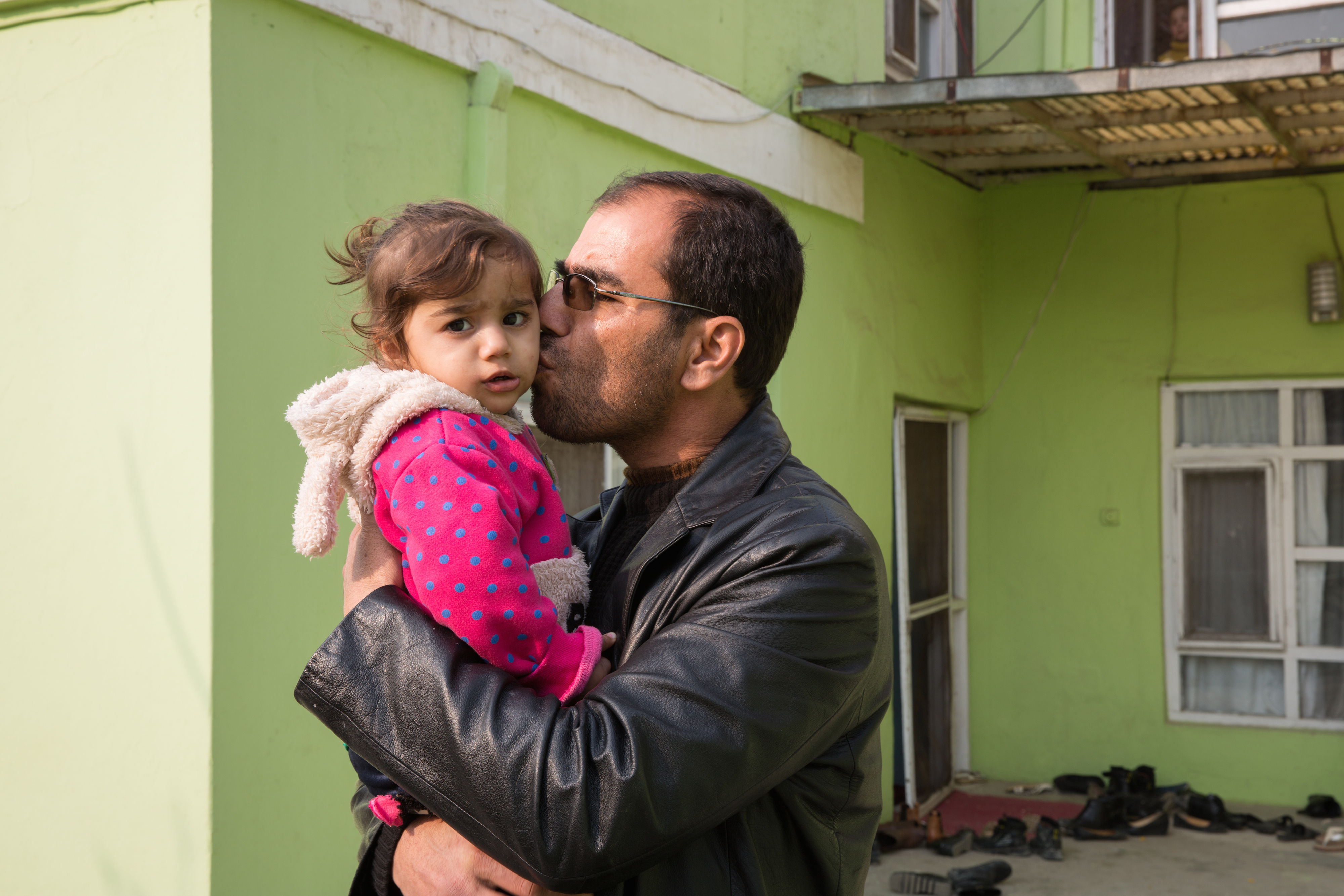 Dr. Wahid Qaderi kisses his daughter outside of his home in Kabul, Afghanistan. Dr. Qaderi talks about his family's decision to leave Afghanistan in the film "Afghanistan by Choice." Image by Alexandria Bombach. Afghanistan, 2016. Afghanistan by Choice