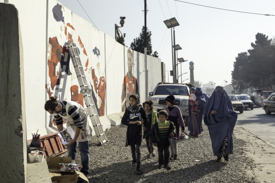 Omaid Sharifi paints a mural of the Afghan soccer team as pedestrians pass by on the streets of Kabul, Afghanistan. Image by Alexandria Bombach. Afghanistan, 2016. Media file: afghanistan_by_choice.jpg