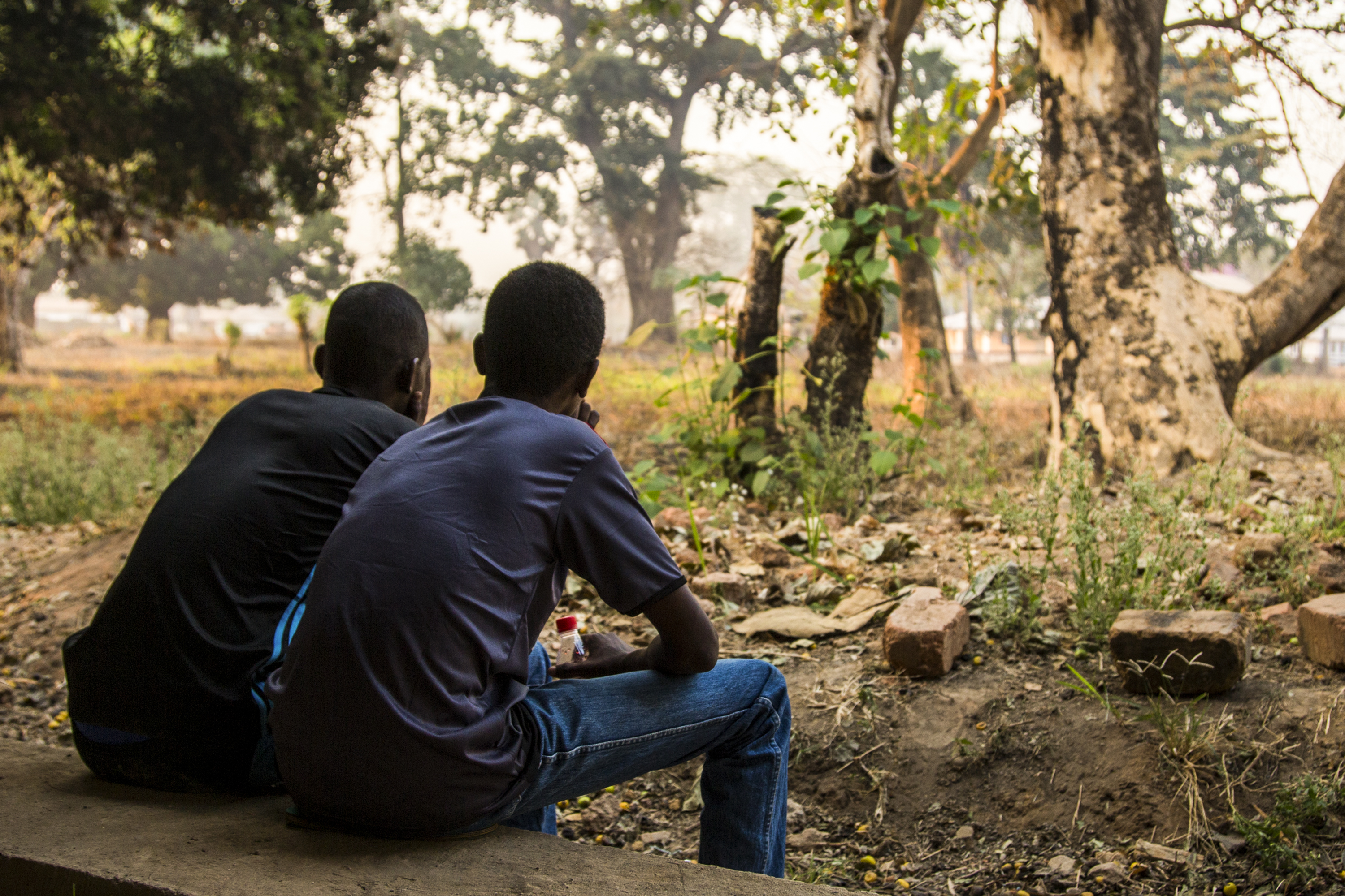 Hassan, left, and another former child soldier sit together in Kaga Bandoro, a rebel-held town in the Central African Republic. Armed groups had released the pair just several weeks earlier. Image by Jack Losh. Central African Republic, 2018.