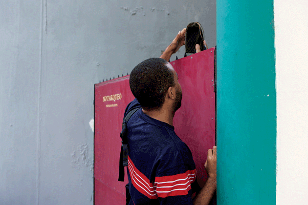 Maykel Molina Gutiérrez delivers El Paquete to a customer during his weekly round. Image by Alexa Hoyer. Cuba. Maykel Molina Gutiérrez delivers El Paquete to a customer during his weekly round. Image by Alexa Hoyer. Cuba.
