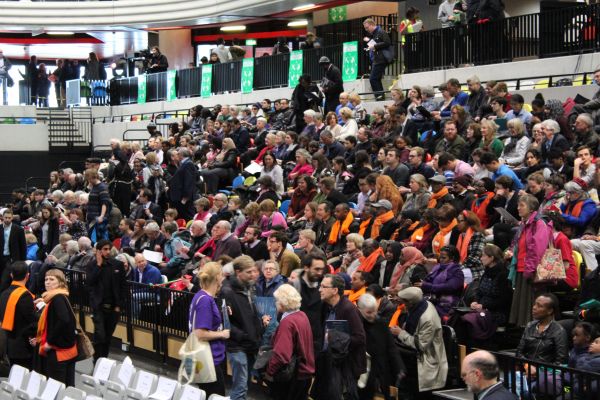 The members of the group Migrants Organise take their seats in a London arena for a mayoral debate. Image by Abe Kenmore. United Kingdom, 2016. Migrants Organise at Mayoral Debate
