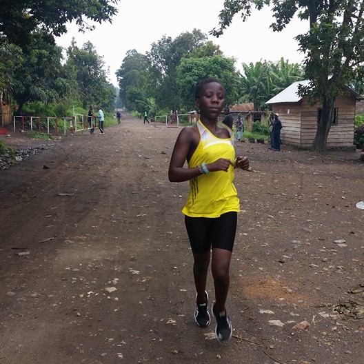 Beatrice Kamuchanga runs down the main road in Kirotshe. Each morning she trains in the mountains surrounding Lake Kivu as she prepares to run the 5000 meter race in the 2016 Olympic games. Image by Makorobondo Dee Salukombo. Democratic Republic of Congo, 2015. Beatrice Kamuchanga runs down the main road in Kirotshe, Democratic Republic of Congo.