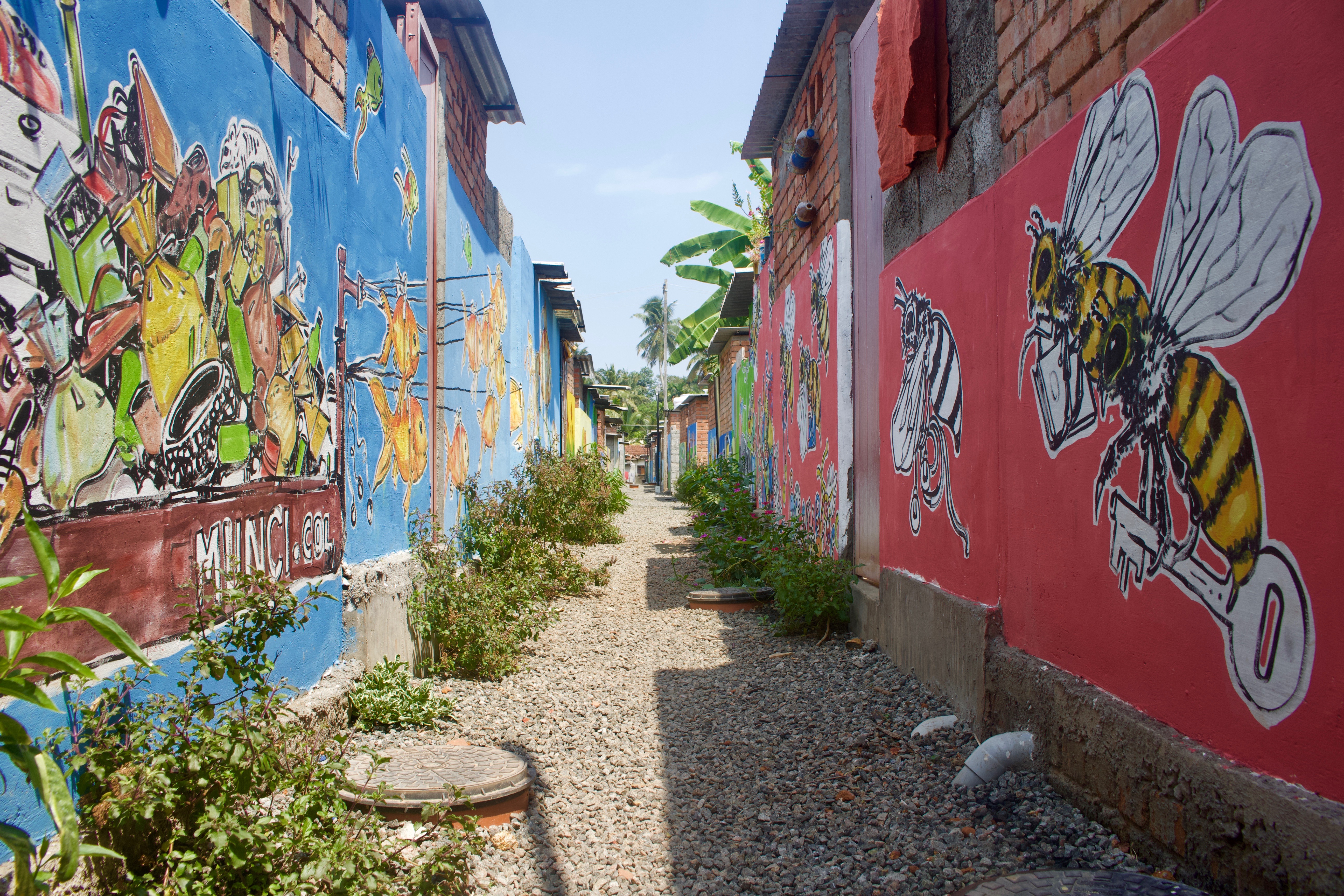 Murals line the area behind 52 homes in Chathanad Colony in Alleppey, Kerala, India. A canal polluted with the community’s waste used to run here, and is now clean, piped, and covered. Image by Katelyn Weisbrod. India, 2019.