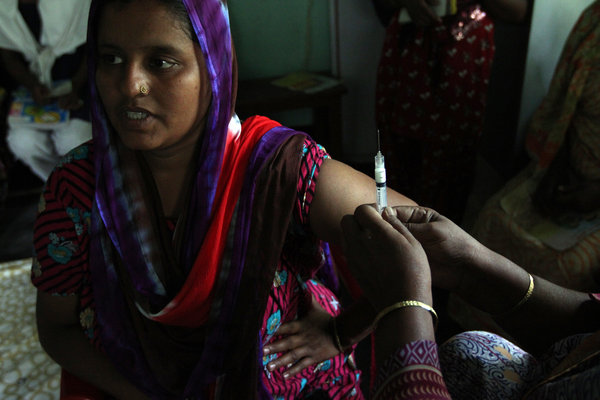 A mother of two in Matlab, Bangladesh, prepares to receive a hormone shot that will protect her from pregnancy for three months. Bangladesh has made access to contraceptives a priority, unlike many fast-growing nations in Africa. Image by Kenneth R. Weiss/Los Angeles Times. Bangladesh 2013.