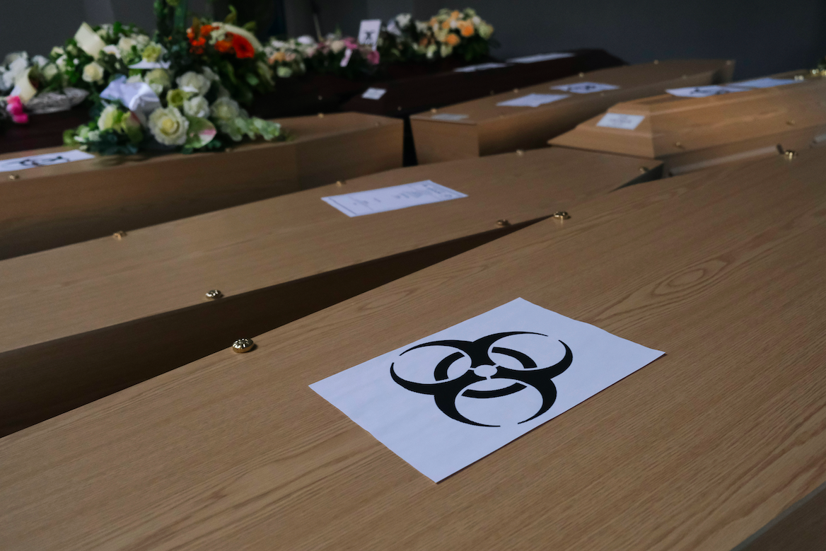 Coffins of COVID-19 victims are marked with a "biohazard" warning sign as they are placed next to each other at the Pompes Funebres Fontaine funeral service company in Gilly, Belgium. Image by Alexandros Michailidis / Shutterstock. Belgium, 2020. Coffins of COVID-19 victims are marked with a "biohazard" warning sign as they are placed next to each other at the Pompes Funebres Fontaine funeral service company in Gilly, Belgium. Image by Alexandros Michailidis / Shutterstock. Belgium, 2020.
