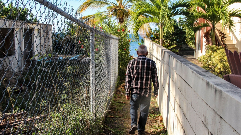 Ismael Guadalupe Ortiz walks between buildings to the beach around the Bravos de Boston neighborhood, where vacation homes, small hotels and Airbnbs proliferate. Image by Kari Lydersen. Puerto Rico, 2019. Ismael Guadalupe Ortiz walks between buildings to the beach around the Bravos de Boston neighborhood, where vacation homes, small hotels and Airbnbs proliferate. Image by Kari Lydersen. Puerto Rico, 2019.