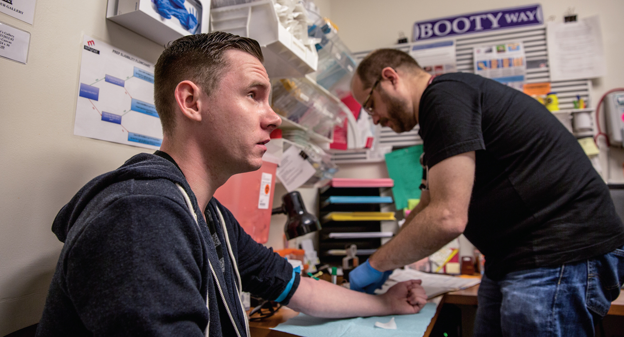 After this test showed Shane Ryan's blood was negative for the AIDS virus, Magnet's nurse practitioner Pierre-Cédric Crouch (background) offered him anti-HIV drugs to prevent infection. Image by Drew Bird. United States, 2015. Media file: f1.large_.jpg