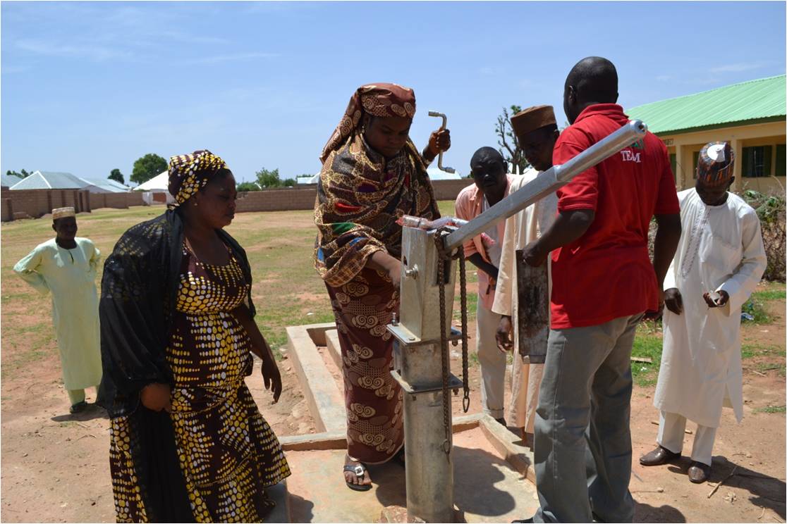 Asabe Issa, 35, a teacher, fixes a broken water pump at Hardawa west Primary School. Image by Ameto Akpe. Nigeria, 2013. Media file: asabe_issa_fixing_a_water-pump.jpg