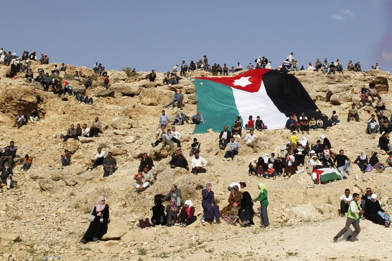 A group of Palestinian refugees gathered around a large Jordanian flag. Image by Muhammad Hamed/Reuters. Jordan, 2014.