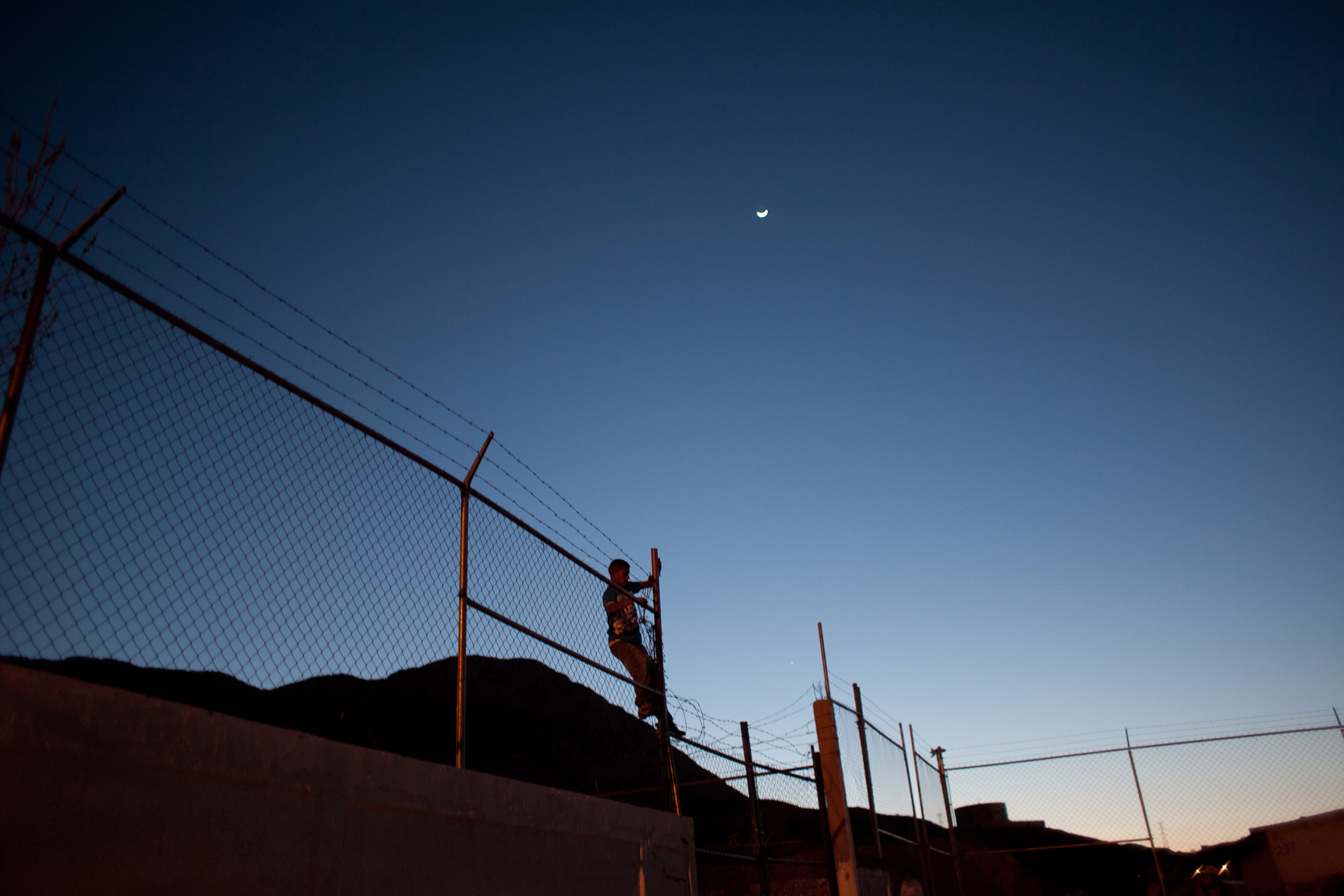 A member of the Novenos climbs a fence. The city closed the football courts where they hang out in an effort to keep the neighborhood safe. They gather there anyway and worry that if attacked they would be unable to flee. Image by Dominic Bracco II. Mexico, 2016. A member of the Novenos climbs a fence. The city closed of the football courts where they hang out in an effort to keep the neighborhood safe. They gather there anyway and worry that if attacked they would be unable to flee. Image by Dominic Bracco II. Mexico, 2016.