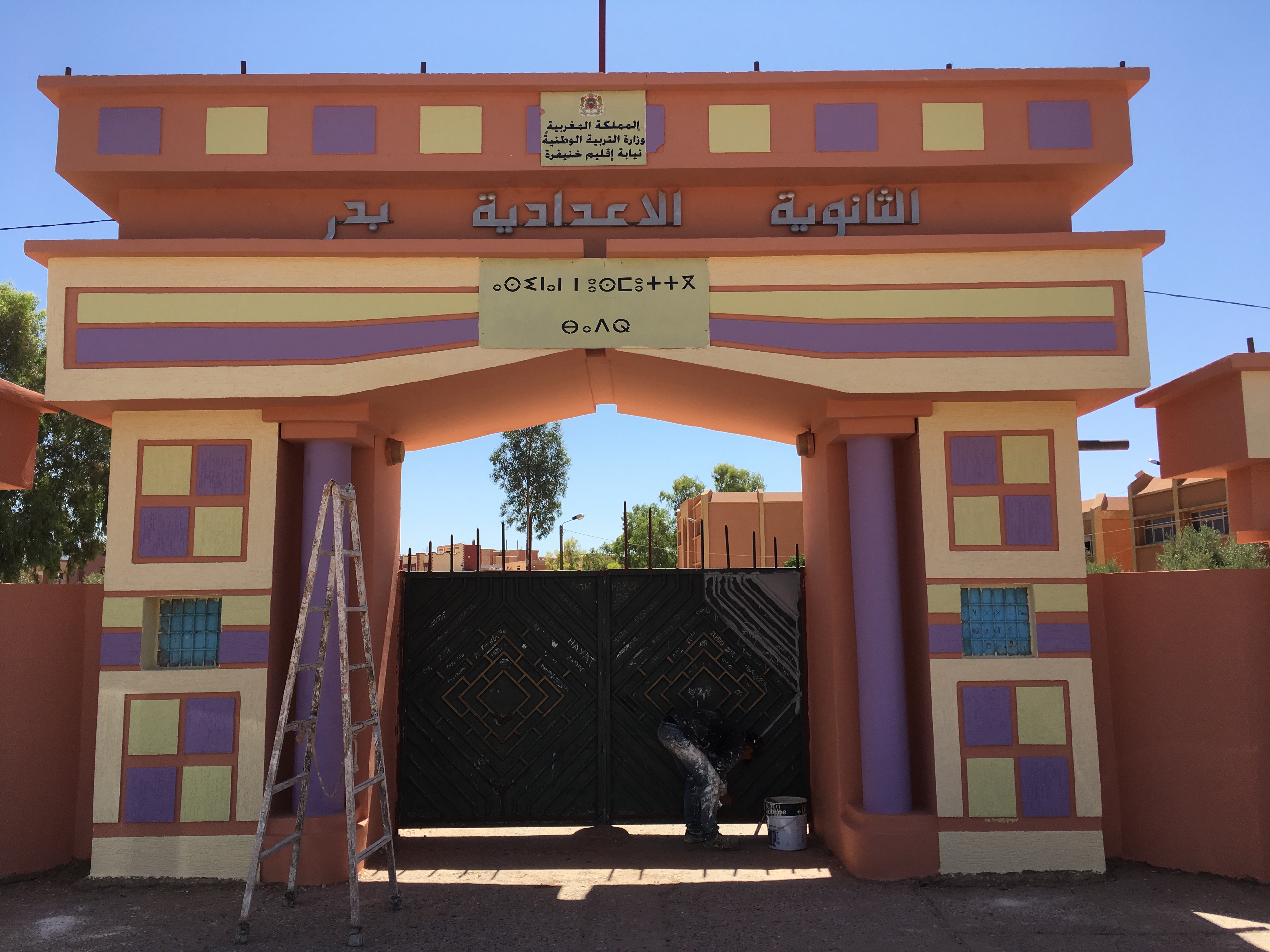 Workman puts finishing touches repainting the entrance to a Moroccan middle school. Workman adds finishing touches to the entrance to a Moroccan middle school. Morocco's new Minister of Education, Mohamed Hassad, has begun his tenure with a focus on achieving immediate results in advancing an ambitious program of reform, including significant changes to Morocco's language education policies. Another initial measure he took was to order all primary and middle schools to be repainted in bright pastels for the beginning of the school year, pictured here. Image by Gareth Smail. Morocco, 2017.