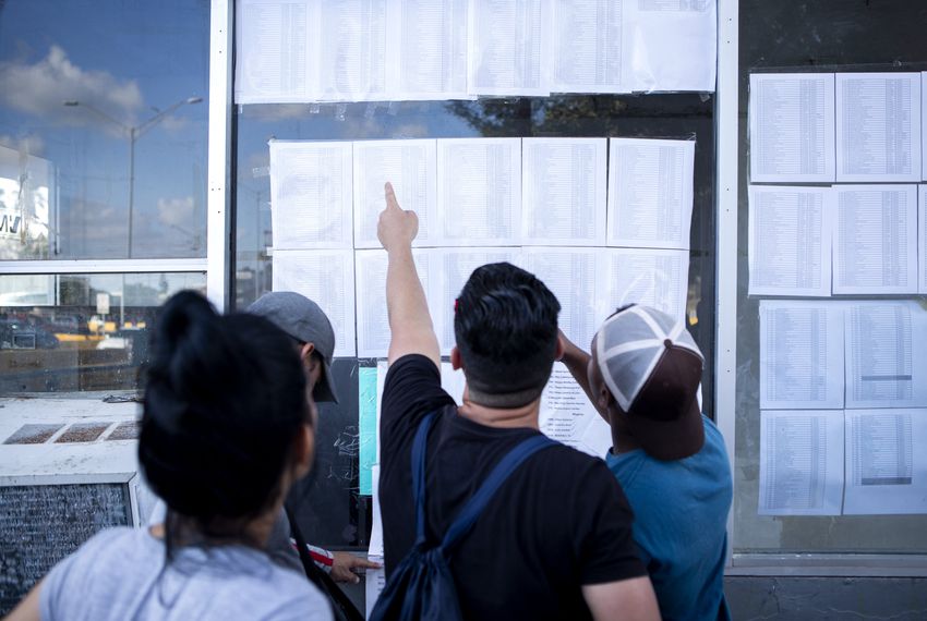 Cuban migrants look at a list of asylum seekers near the Gateway International Bridge in Matamoros, Tamaulipas. Image by Miguel Gutierrez Jr. Mexico, 2019. Cuban migrants look at a list of asylum seekers near the Gateway International Bridge in Matamoros, Tamaulipas. Image by Miguel Gutierrez Jr. Mexico, 2019.