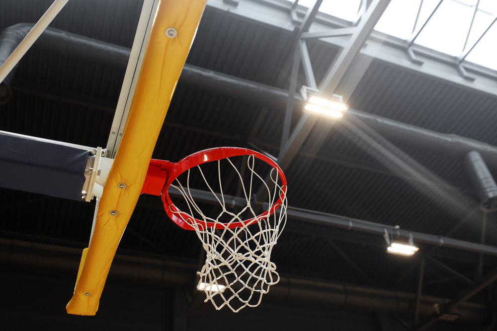 Basketball hoop in the sports center against the dark ceiling. Image by Andrew Makedonski / Shutterstock. Basketball hoop in the sports center against the dark ceiling. Image by Andrew Makedonski / Shutterstock.