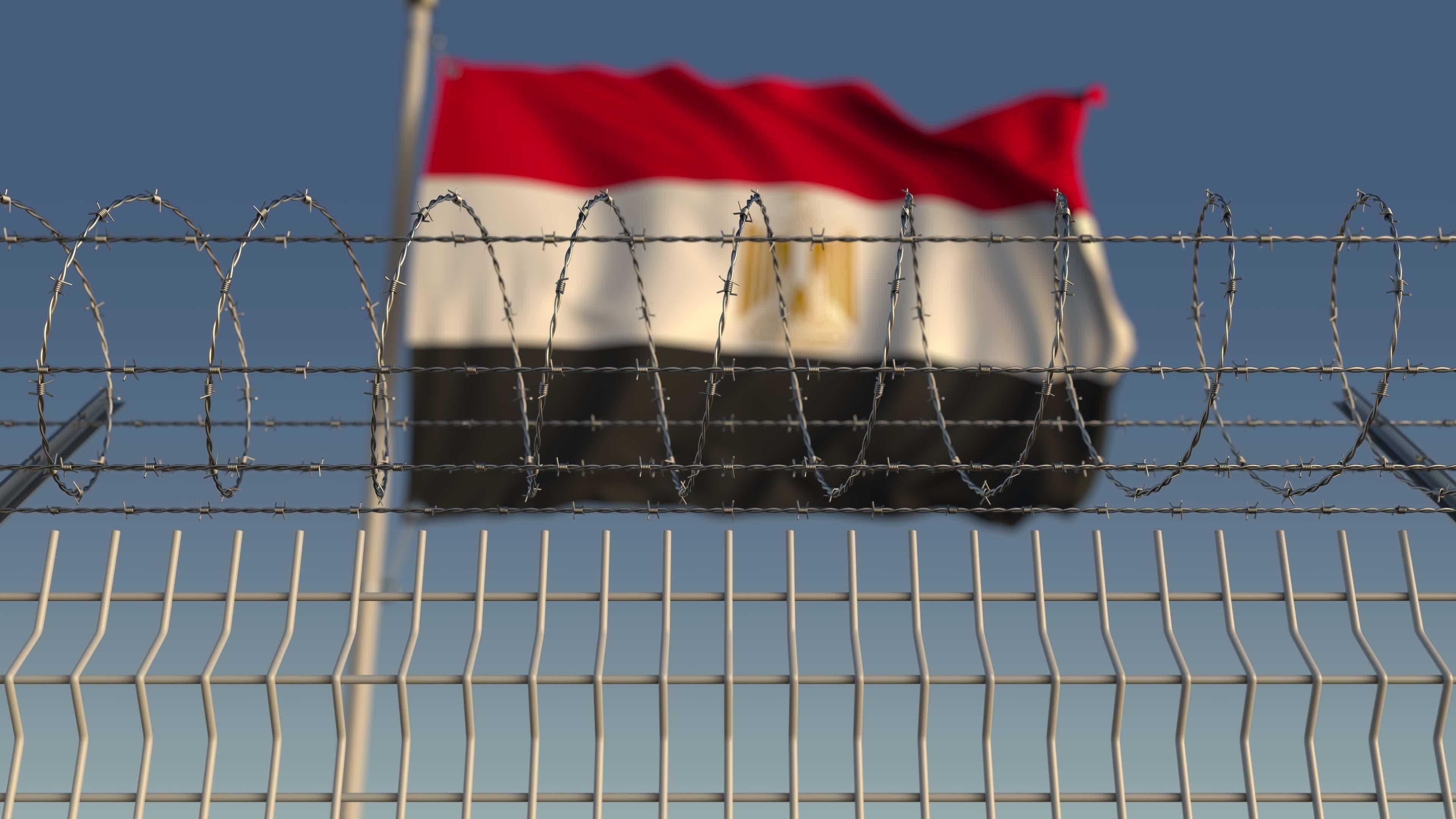 Blurred waving flag of Egypt behind barbed wire fence. Image by Novikov Aleksey. Undated. Blurred waving flag of Egypt behind barbed wire fence. Image by Novikov Aleksey. Undated.
