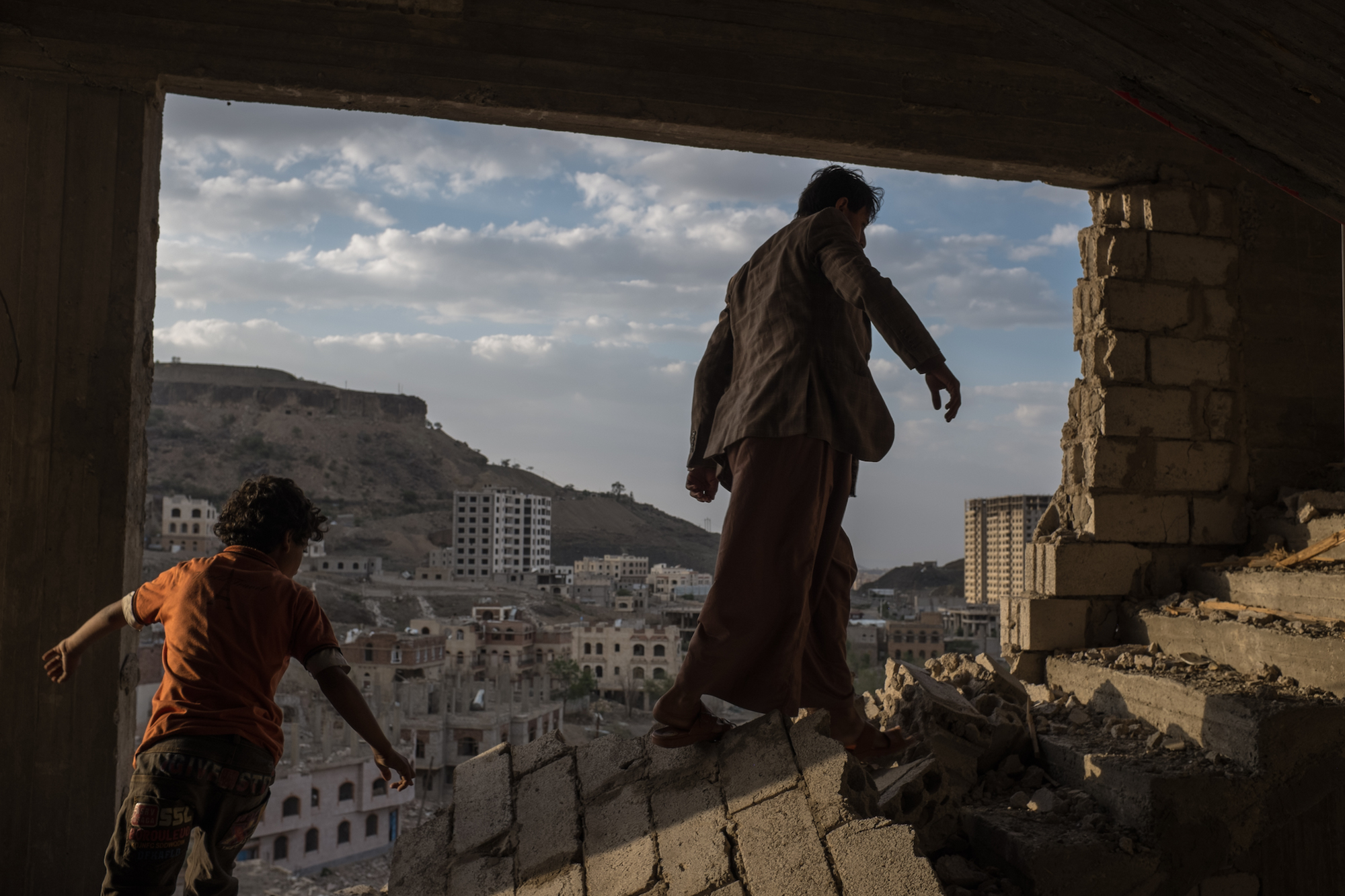 Yemeni brothers climb the broken stairs of an apartment building damaged by airstrikes in the Faj Attan district of Sana, Yemen, in August 2015. Image by Alex Potter. Media file: potter_alex_07.jpg